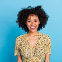 Cute young African American female with fine hair follicles wearing a curly hairdo styled with coconut oil and hot tools.