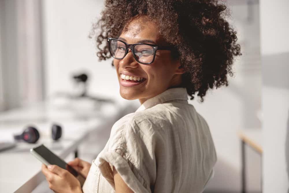 A lovely young African woman with brown skin and bouncy natural curls researching sebaceous glands on her iPhone.