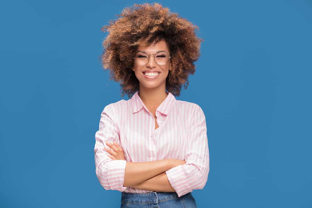 Cute African American female after using hair dye leftovers stored in a dye tube within an air-tight container.