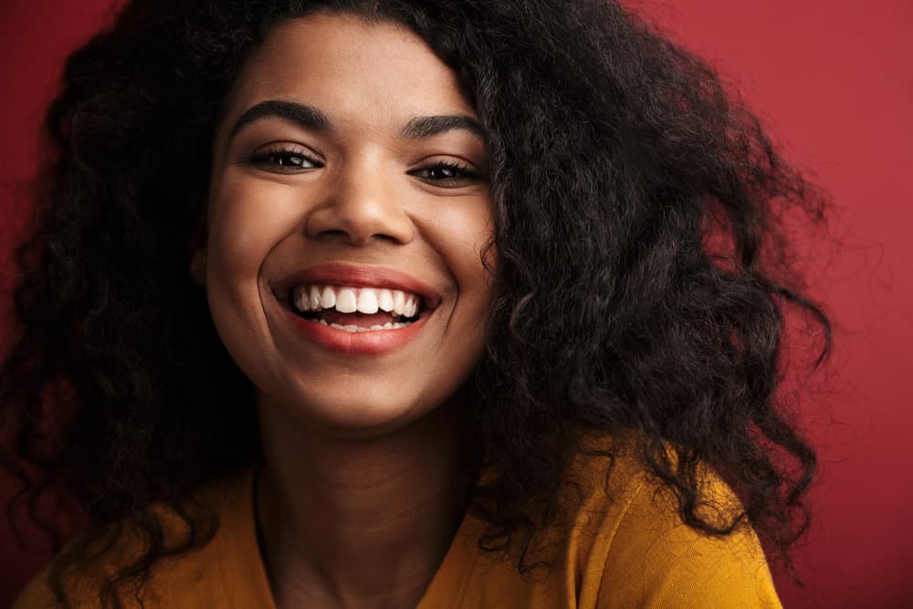 A young cheerful black girl after taking down a loose ponytail styled her hair with a paddle brush.