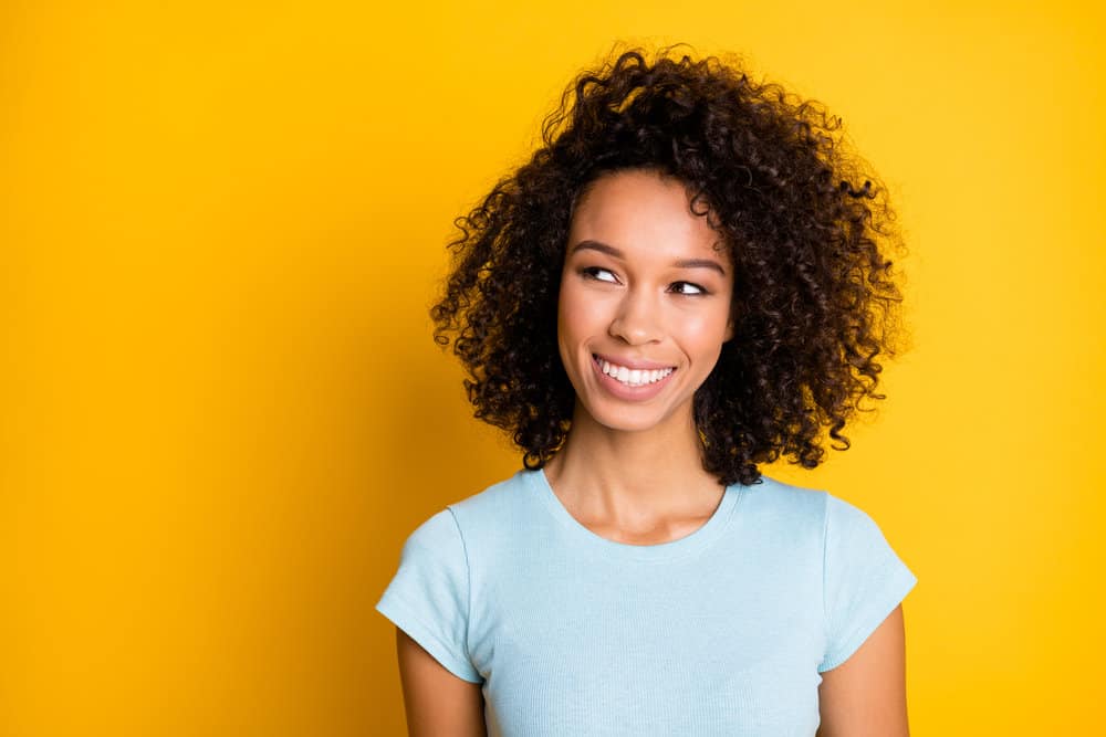 Young black girl with medium-brown dark hair dye on her bouncy natural curls following a bleach bath treatment.