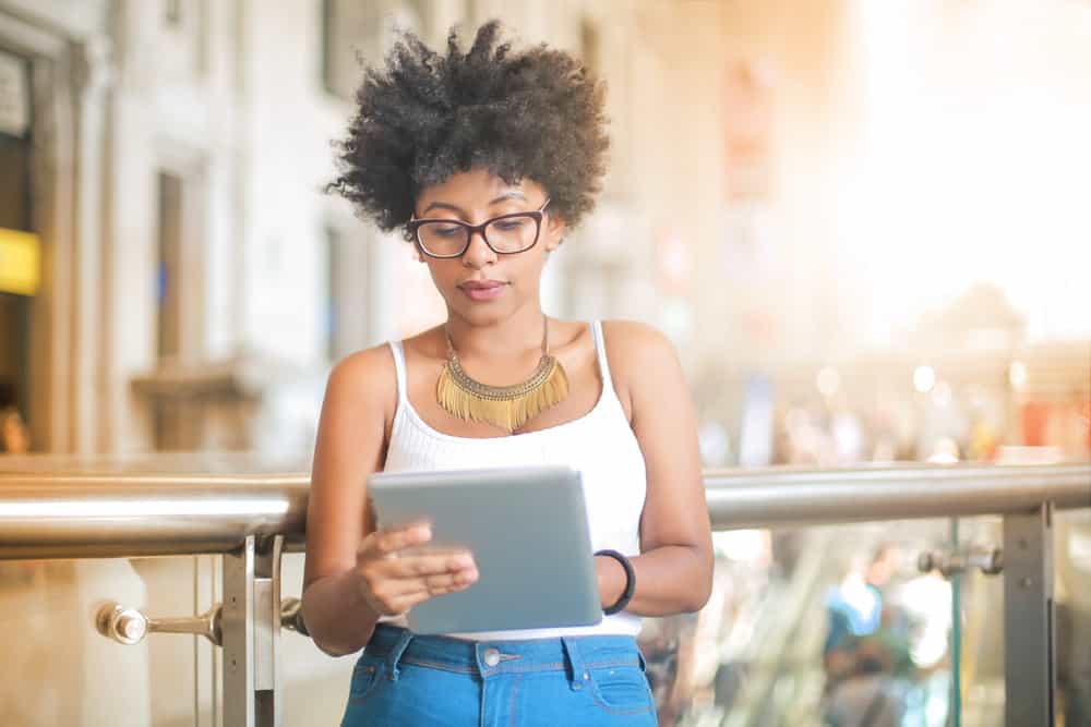 Young black woman looking up Great Clips prices and comparing them to other hair salons, like Fantastic Sam.