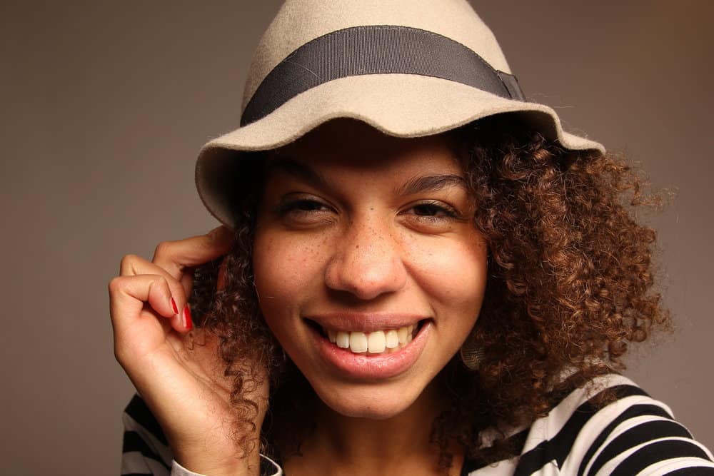 African American female suffering from dandruff Malassezia her favorite baseball cap and stylish cap on the weekend.