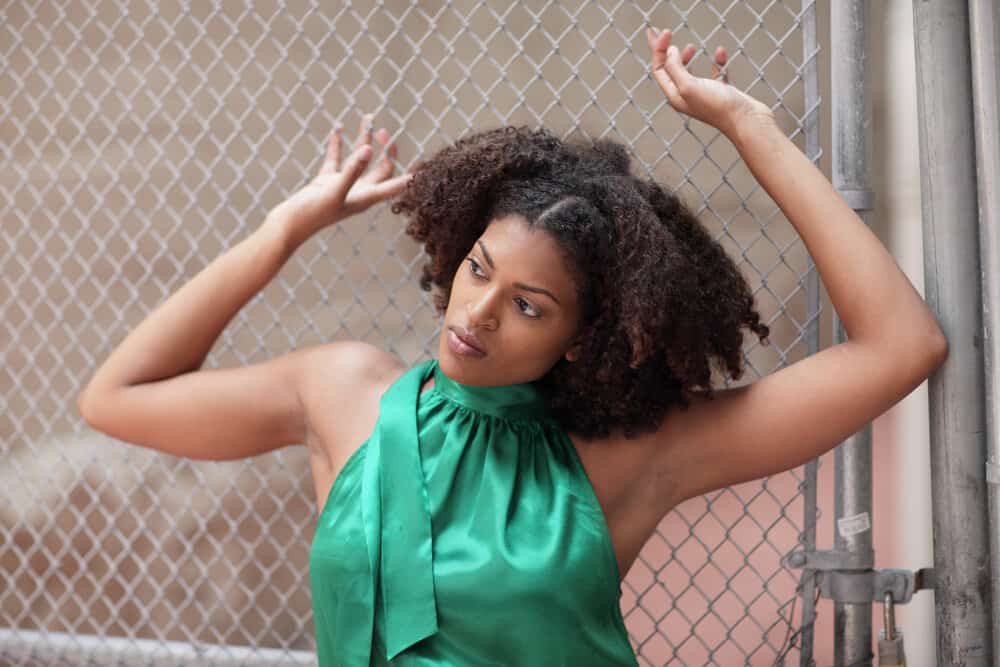 Young black girl with thick hair that has seen her hair grow to its maximum length after using natural oils.