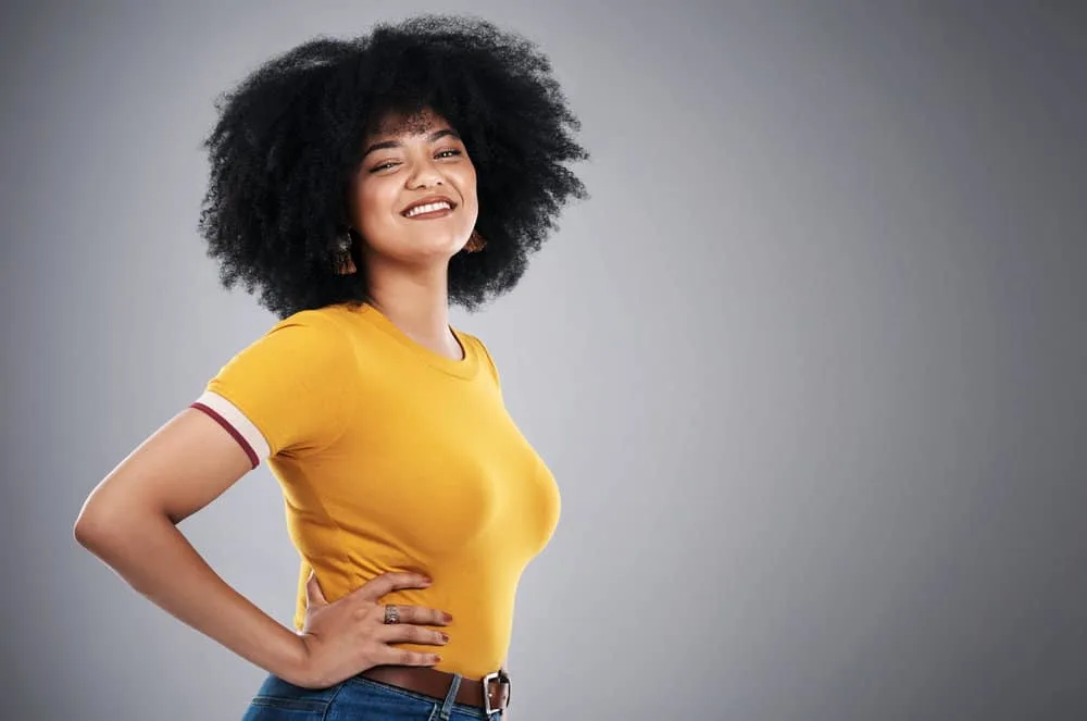 Why Is My Black Hair Turning Gold? 4 Causes & 3 Quick Fixes 2 A young woman with dark brown hair due to melanin pigments starting to turn gold from the sun rays.