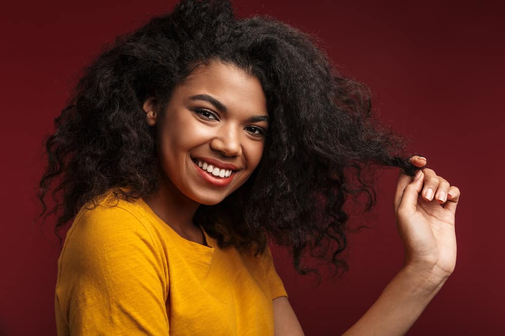 A beautiful young black girl with dry hair that was styled with anti-frizz heat protectant hair spray while flat ironed.