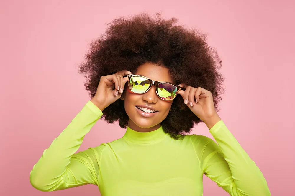 Top 20 Y2K Hairstyles: Braids, Bangs, Short Hair, and More 19 A young African woman with medium-dense hair wearing a curly hairstyle was sprayed with texture spray.