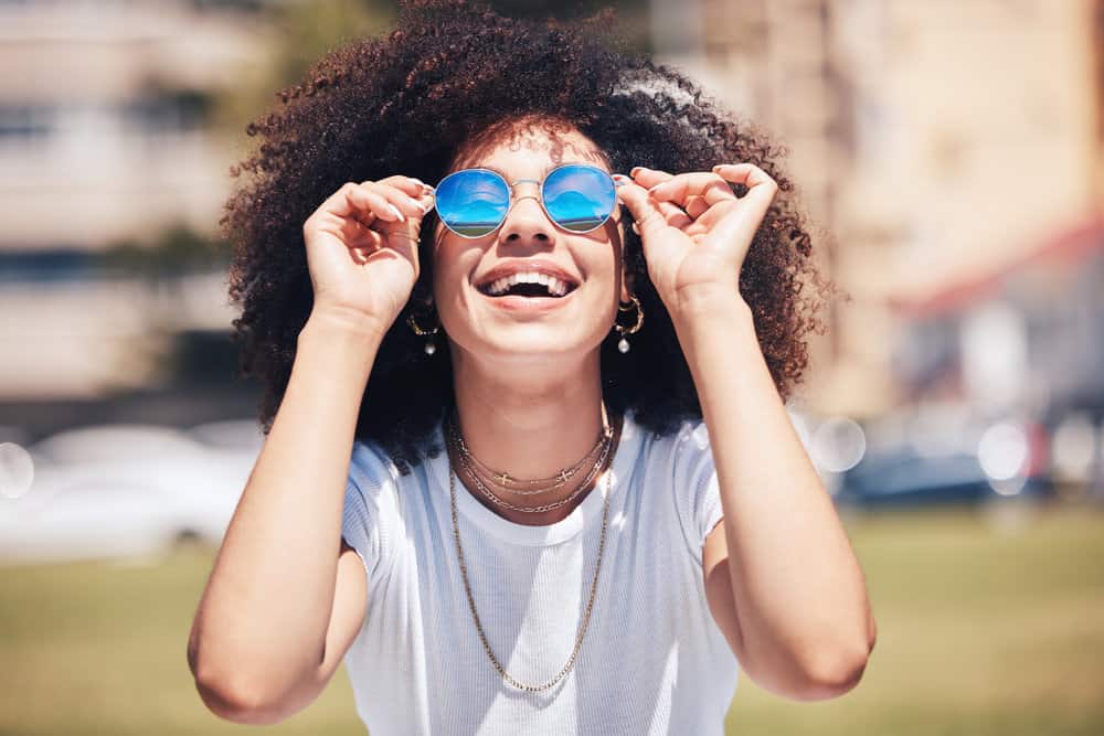 A happy black girl with curly hair follicles has been eating a healthy and balanced diet to promote hair growth.