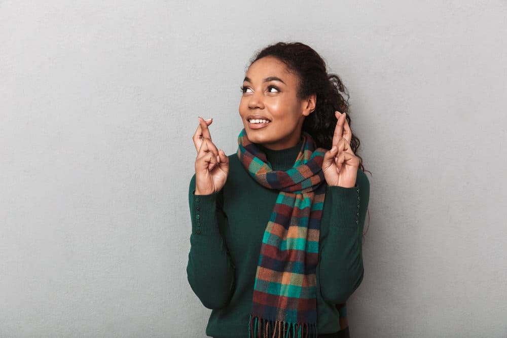 A lady holding her fingers crossed while posing for a photo after using a density thickening shampoo.