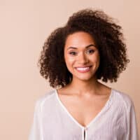 A cheerful young black girl with healthy hair styled her natural curls with virgin coconut oil and essential hair oils.