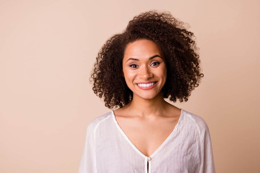 A cheerful young black girl with healthy hair styled her natural curls with virgin coconut oil and essential hair oils.