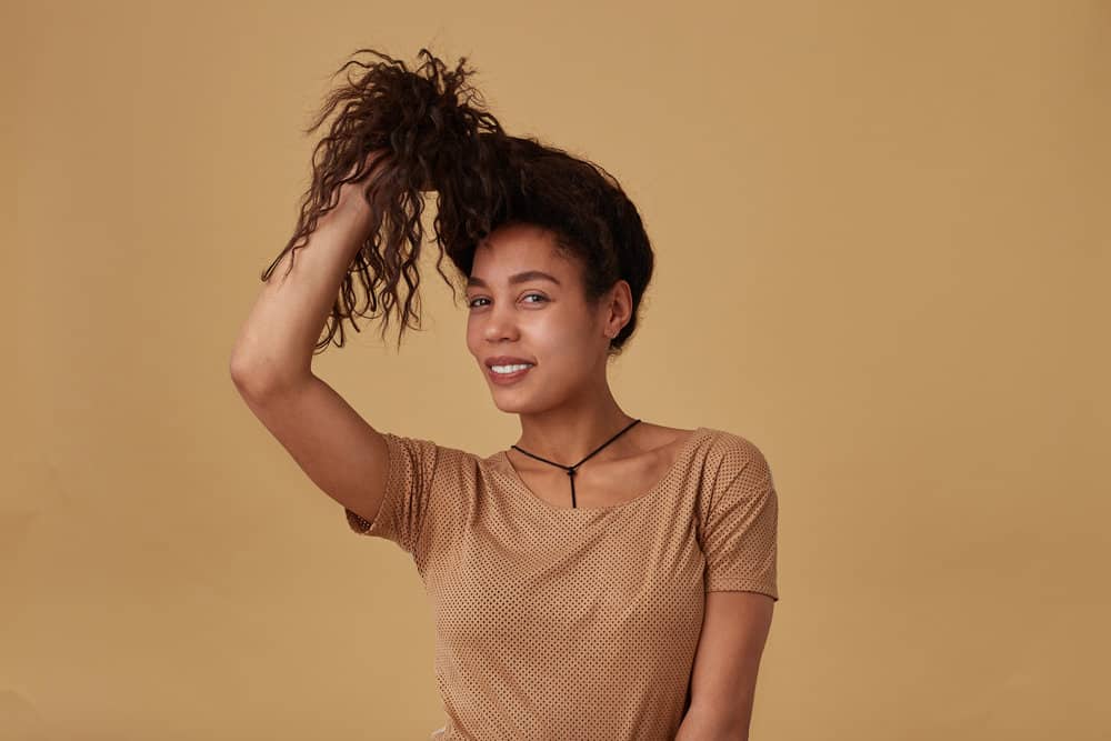 A positive young lady after rough-drying her curly hair in small sections for a series of YouTube videos.