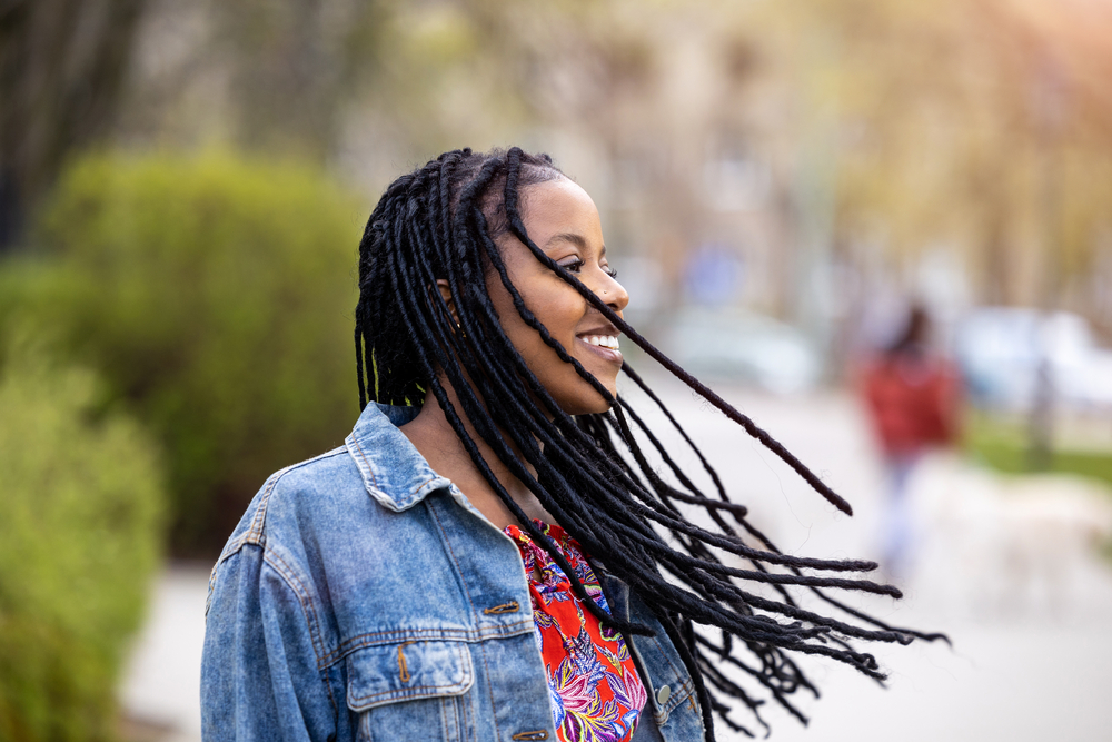 A gorgeous young black female with 4A hair wearing a dreadlock style created with a strong comb at a salon.