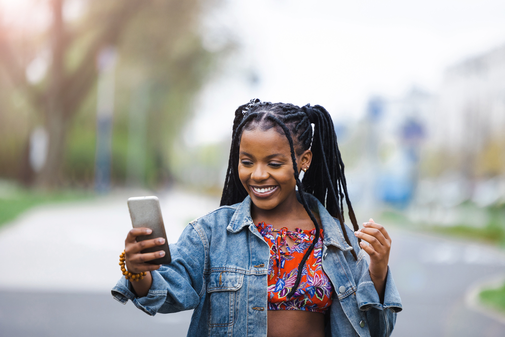 A cute young female with locked hair researching the best tips on how to remove dreadlocks with removal cream.