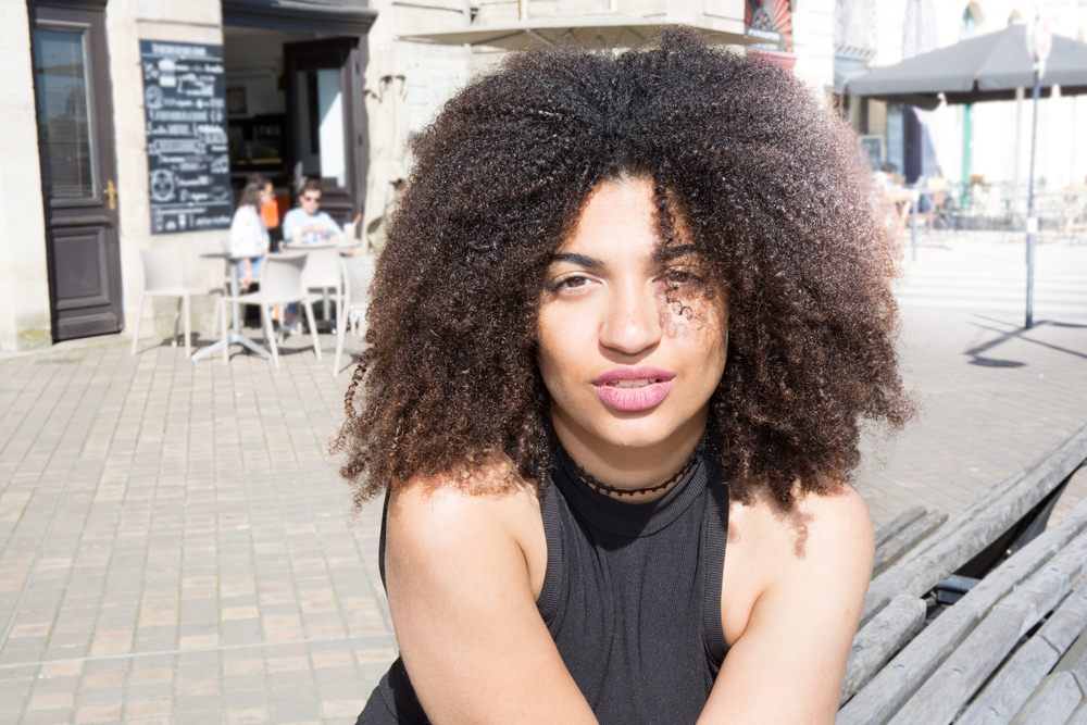 African American lady with dark brown curly hair treated with a hair growth mix (neem oil and peppermint oil).