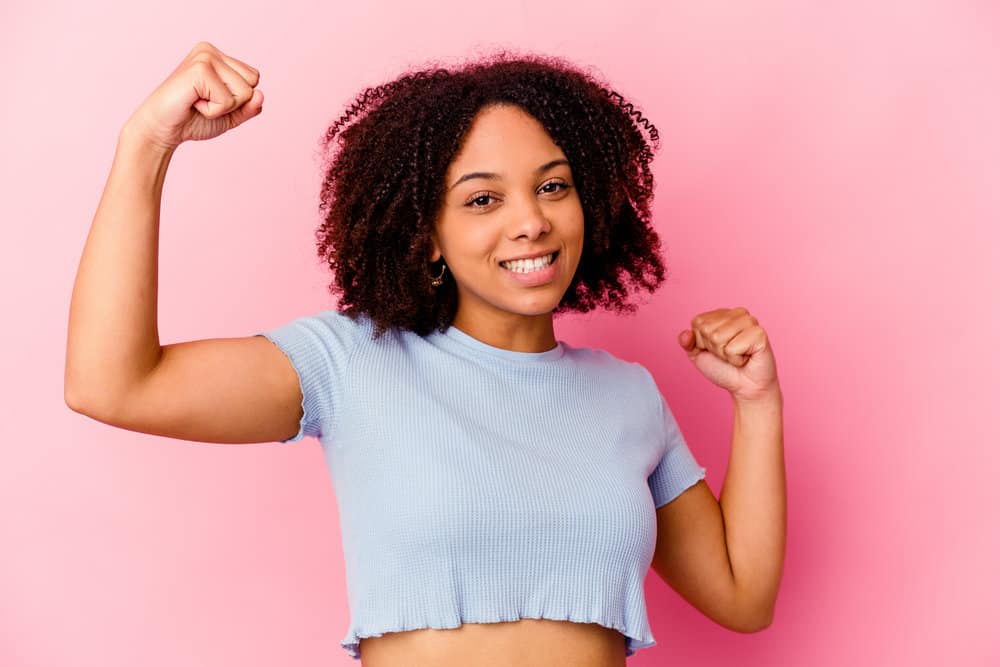 African American girl after drying her wet hair and using a leave-in to retain moisture on kinky hair type.