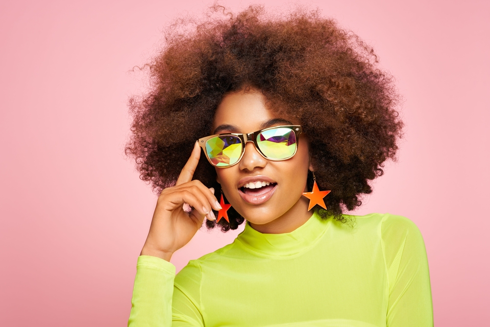 A young lady wearing a kinky afro created by blow-drying her dark brown curls.