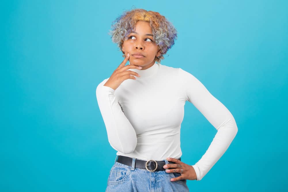 A curious lady wearing her hair blonde, orange and blue after undergoing a DIY dyeing process with brassy tones.