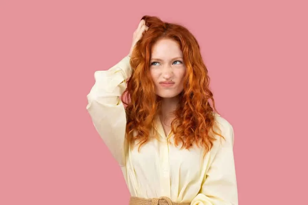 What Is 2A Hair? How To Take Care of It, Styles, and Products 6 A thoughtful woman with natural curls on her 2A natural texture styled with argan oil and other moisturizing products.