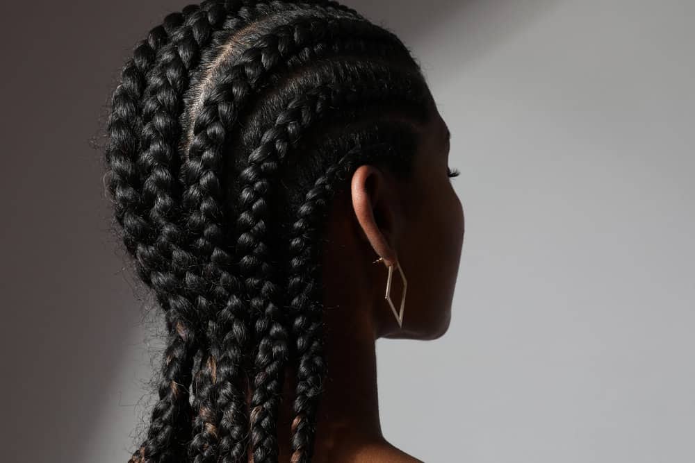 An African female wearing her hair neat in long cornrow braids while she's trying to make her natural hair grow.