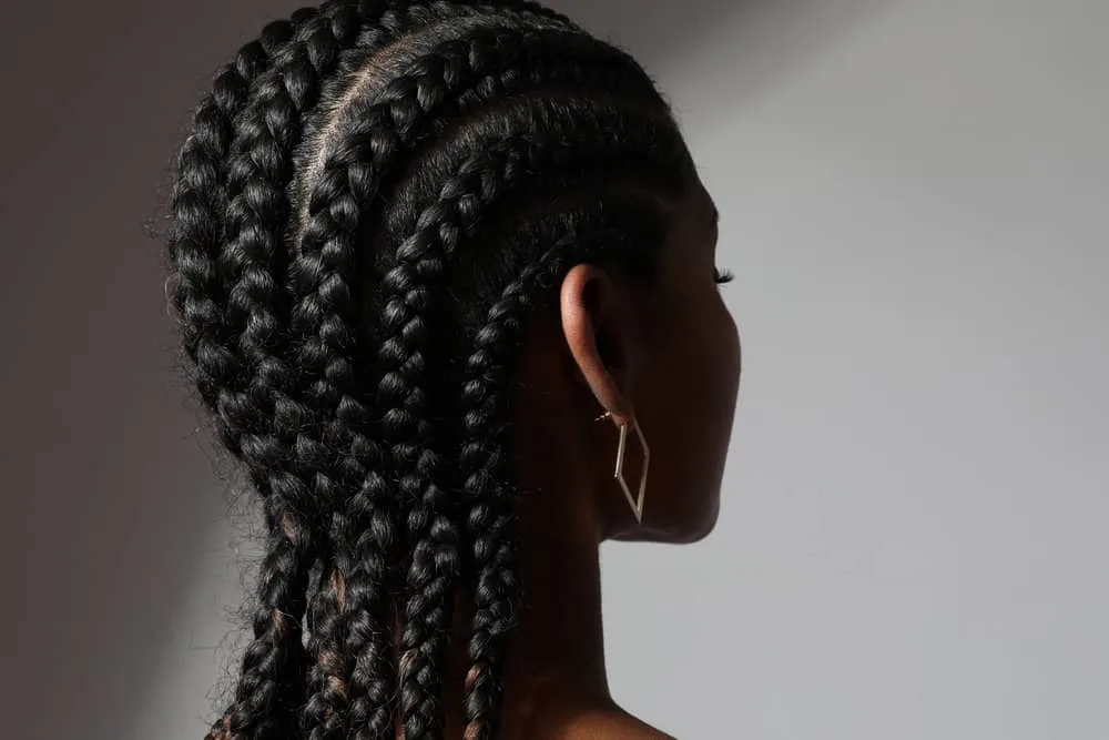 An African female wearing her hair neat in long cornrow braids while she's trying to make her natural hair grow.