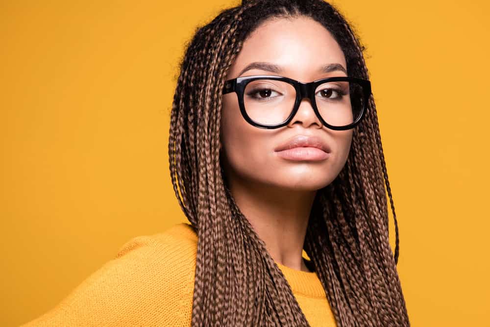 Light-skinned black girl with a pear face shape and a high forehead wearing brown braids on black straight hair.