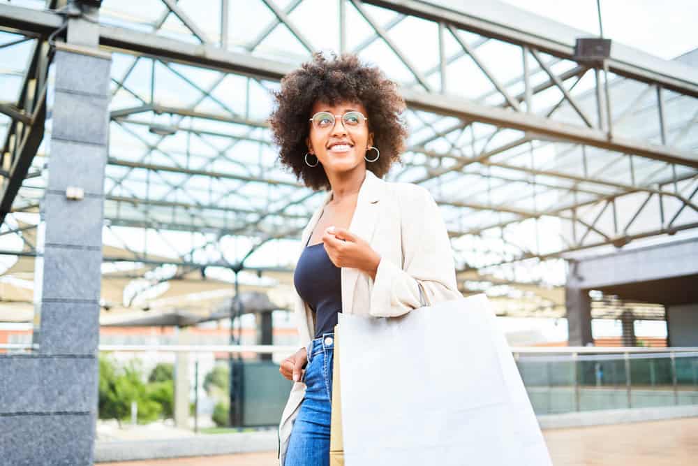 An African American female with dry hair walks to a hair bleaching appointment at a Great Clips location in the mall.