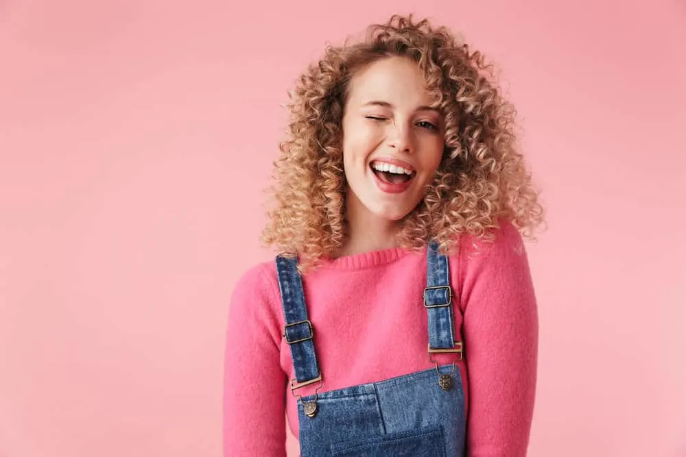 How Long Does Balayage Take to Do or Process In a Salon 6 A young girl with curly hair has a dark brown natural hair color, wondering about the balayage cost for highlighting individual strands.