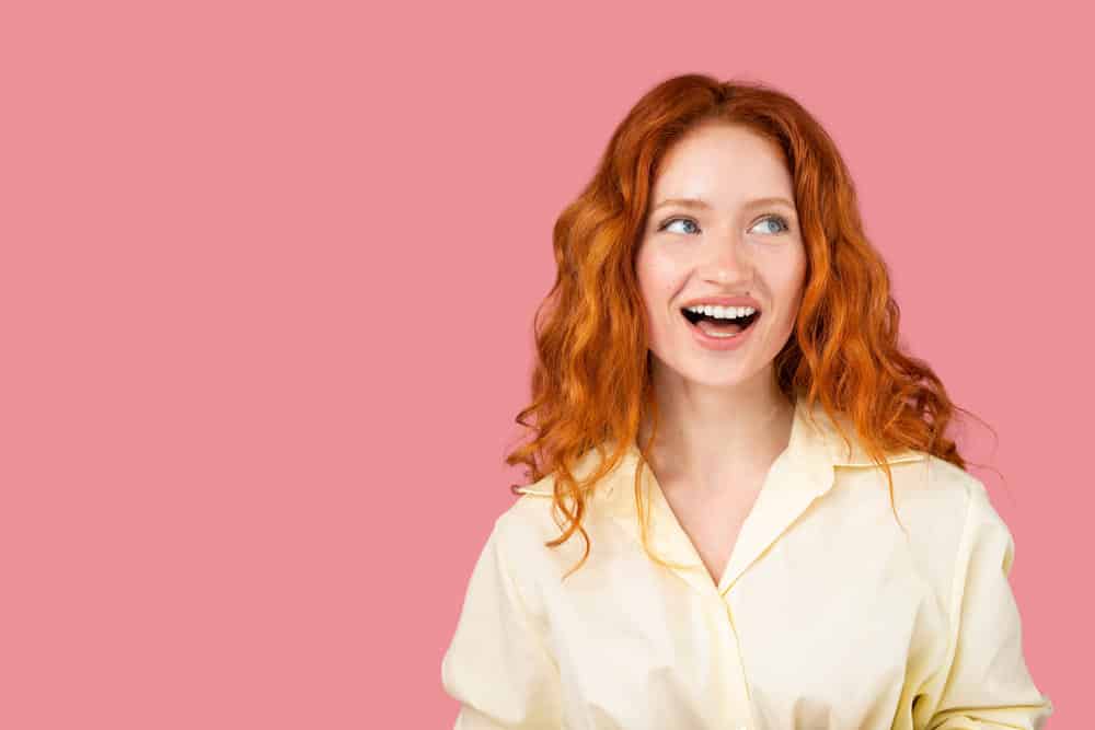 Cute young woman wearing a 90s blowout hairdo created with a blow dryer on her natural loose waves.