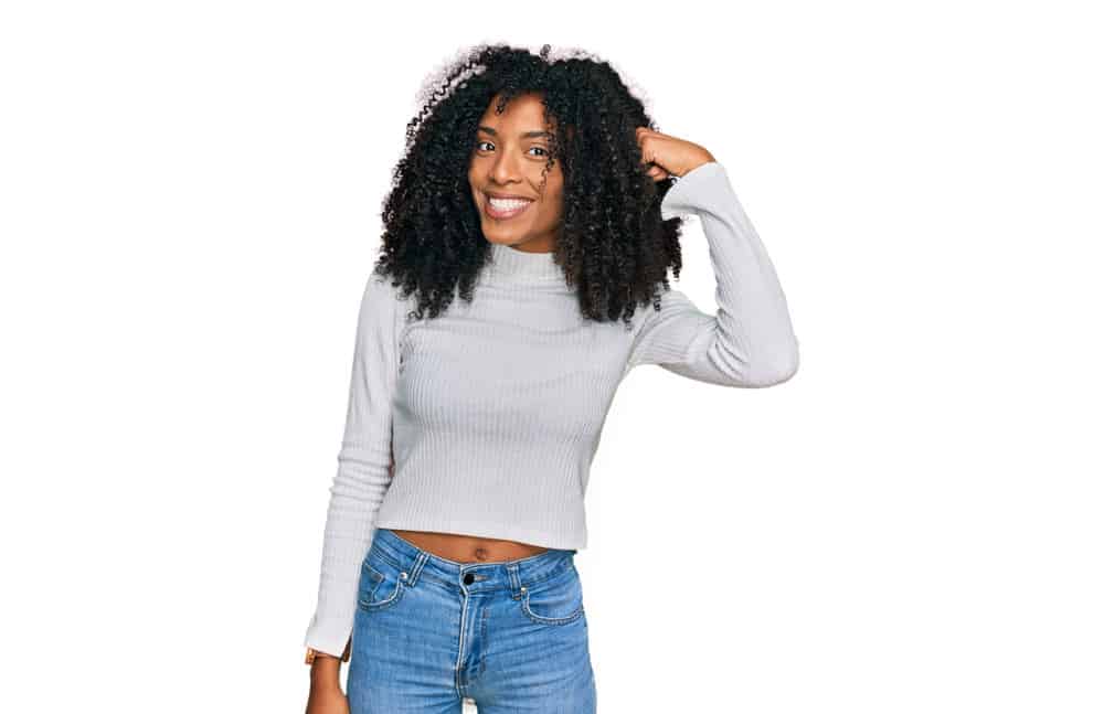 A cute young black girl with natural curls that uses a Curly Girl hair care routine focused on improving hair elasticity.