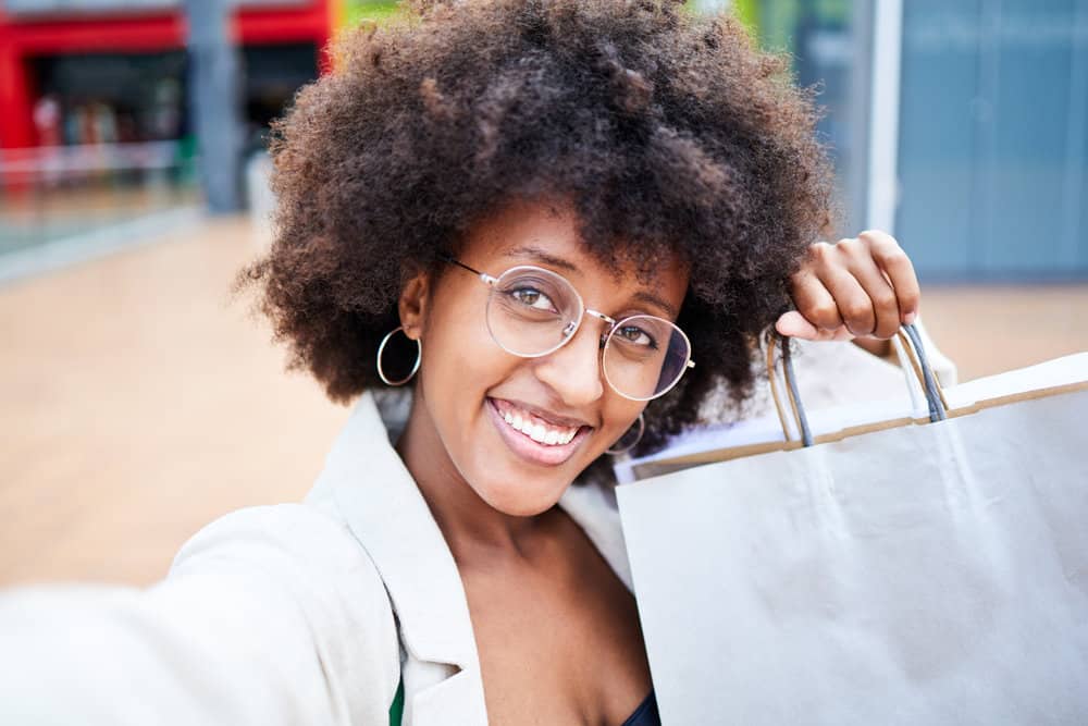 A happy young black woman after getting a hair bleaching treatment on clean hair by a hair colorist.