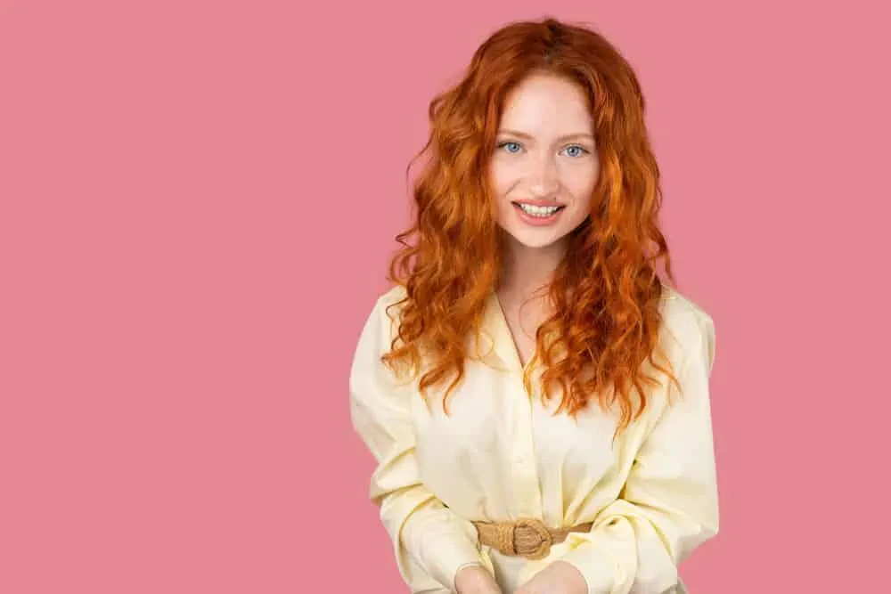 What Is 2A Hair? How To Take Care of It, Styles, and Products 8 A redhead female that's been using hair growth styling tips on her thicker strands with tight waves.