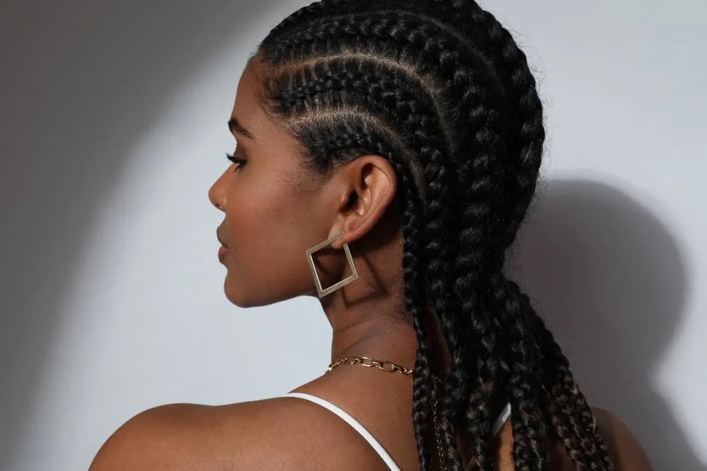 Side-view of a dark-skinned black girl that wears cornrows regularly as her natural hair grows.