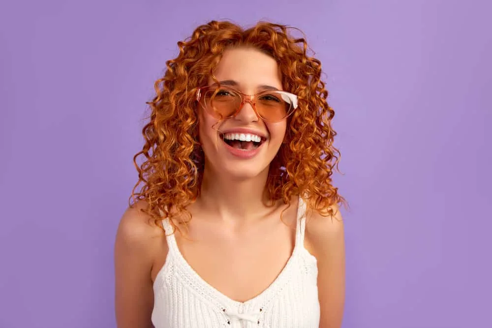 Can I Use Purple Shampoo on Orange Hair? Does It Work? 1 A young white girl posing after using a purple toner with blue pigments to fix orange hair with brassy tones.