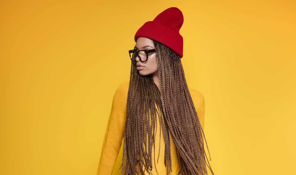 A light-skinned dark girl with a pear face shape and a prominent forehead is wearing brown braids.