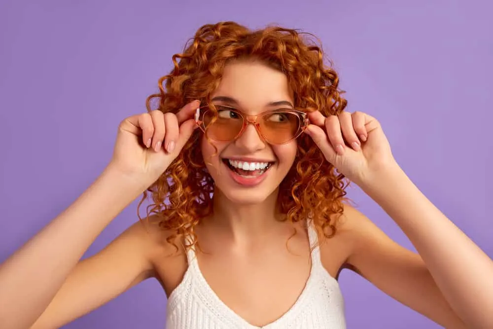 A lady having a good time while posing with sunglasses.