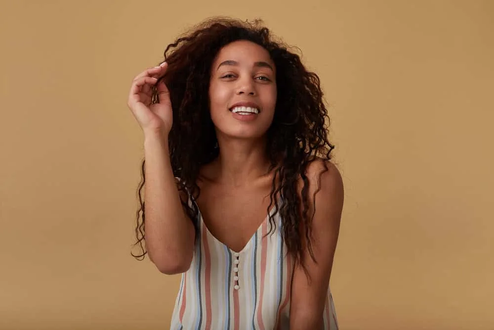 Bumped Ends: How to Bump the Ends of Your Hair at Home 4 A cheerful brown-eyed female has a full head of waves after removing pin curls and a sock bun with a bobby pin.