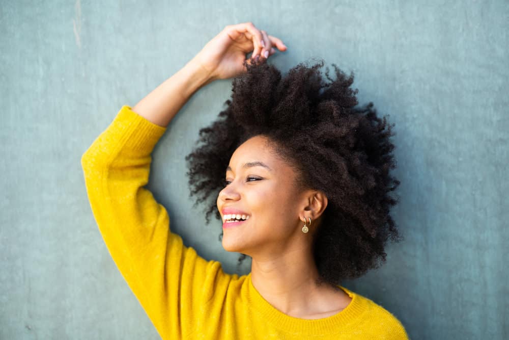 A young black female wearing a tightly coiled afro hairstyle styled with almond oil using the LOC method.