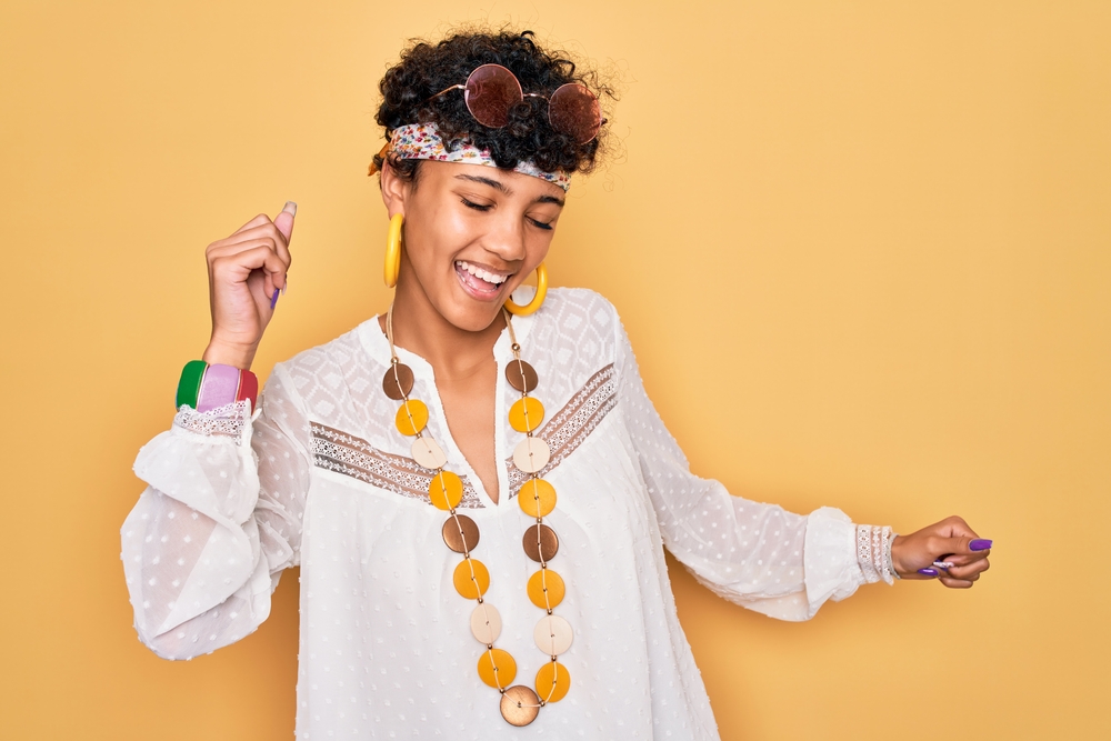 Cute young black woman wearing blonde earrings and a feathered bixie short hairstyle.