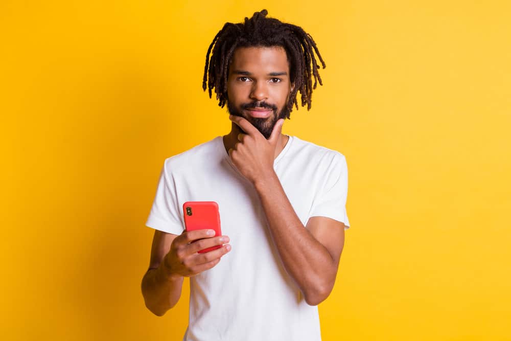 A black man researching how to create dreadlock hairstyles like many popular American rappers.