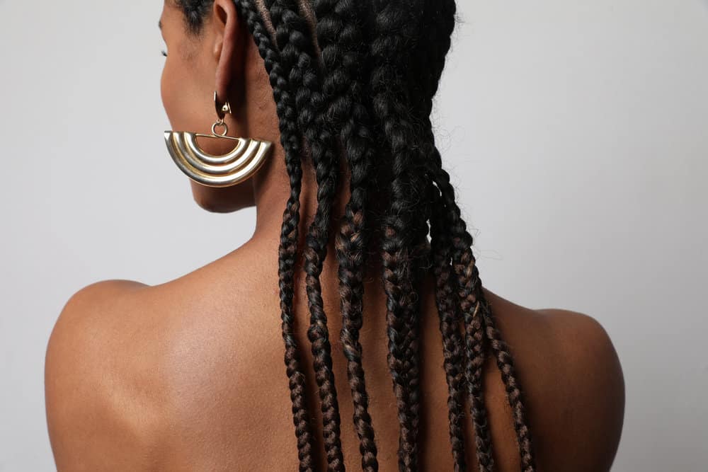 A black lady with an itchy scalp wearing long braids styled with coconut oil and olive oil.