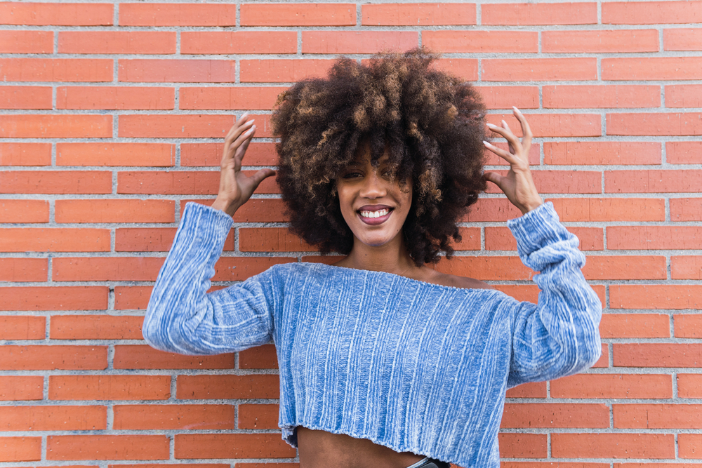 Lady with brown and black natural curls uses a brown rice water routine to encourage new hair growth and hair health.