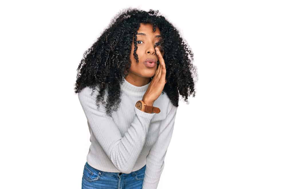 A pretty young African female with natural curls styled with a hair mask and aloe vera for restoring moisture.