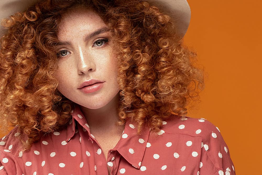 A young lady has reddish platinum blonde curly hair treated with bleaching powder for faster hair growth.