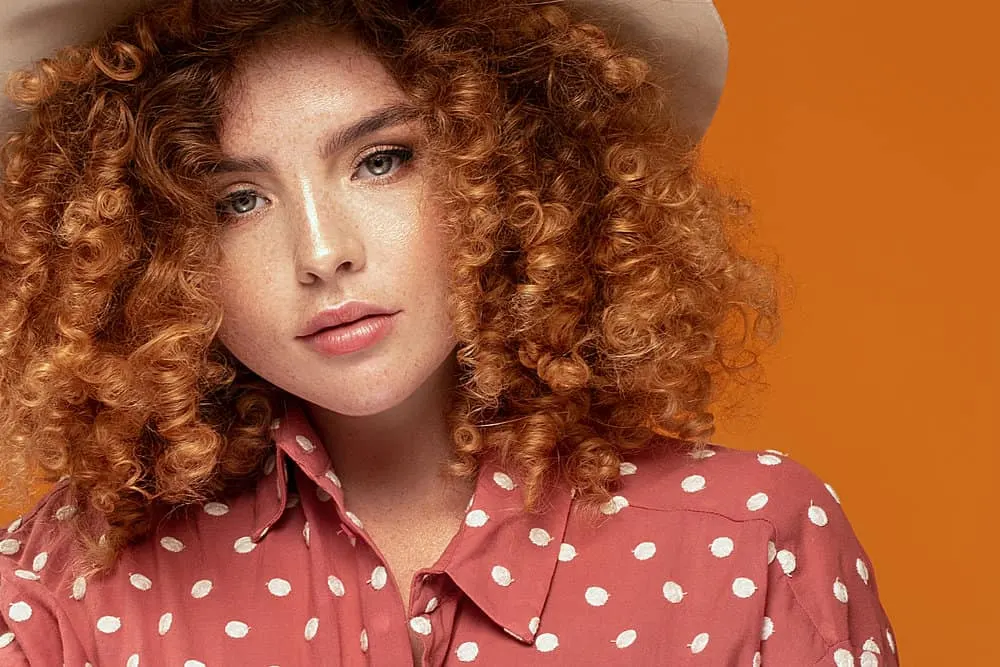 How Long Does Bleached Hair Last and How to Repair Damage 6 A young lady has reddish platinum blonde curly hair treated with bleaching powder for faster hair growth.