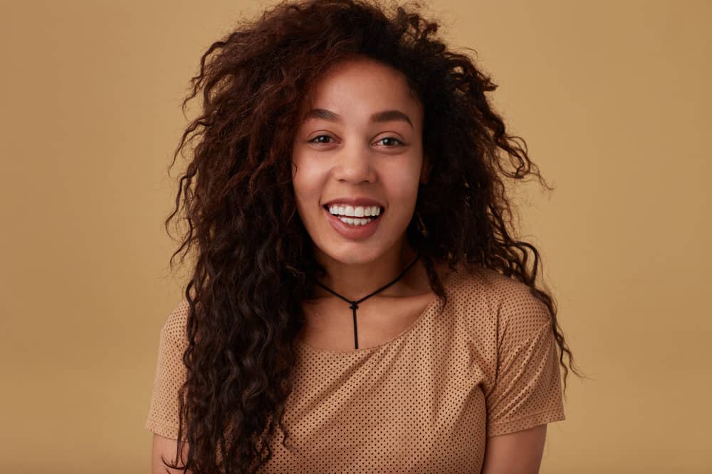 An African American woman after curling her hair from the root to the tip using a wet-to-dry heat styling tool.