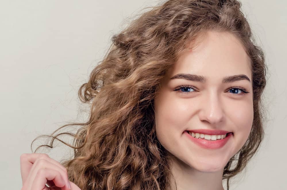A young girl wearing defined curls with a wavy texture styled with a leave-in conditioner for essential moisture.