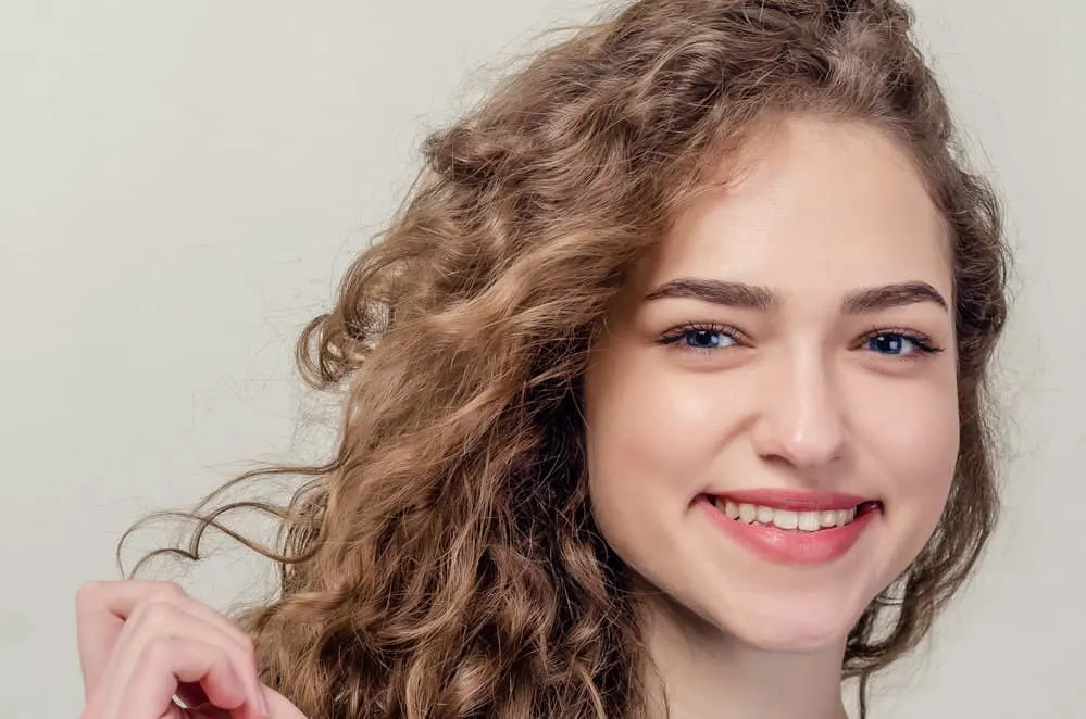 What Is 2C Hair? How To Take Care of It, Styles, and Products 4 A young girl wearing defined curls with a wavy texture styled with a leave-in conditioner for essential moisture.