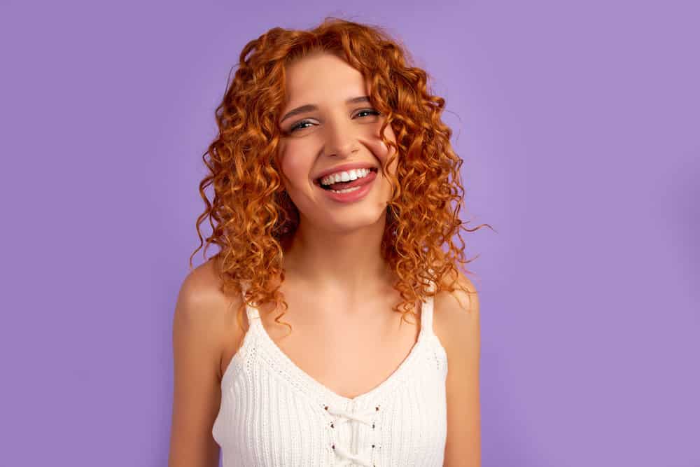 Red-haired girl with brassy hair headed to the hair salon to have it treated with blue shampoos by a hair professional.