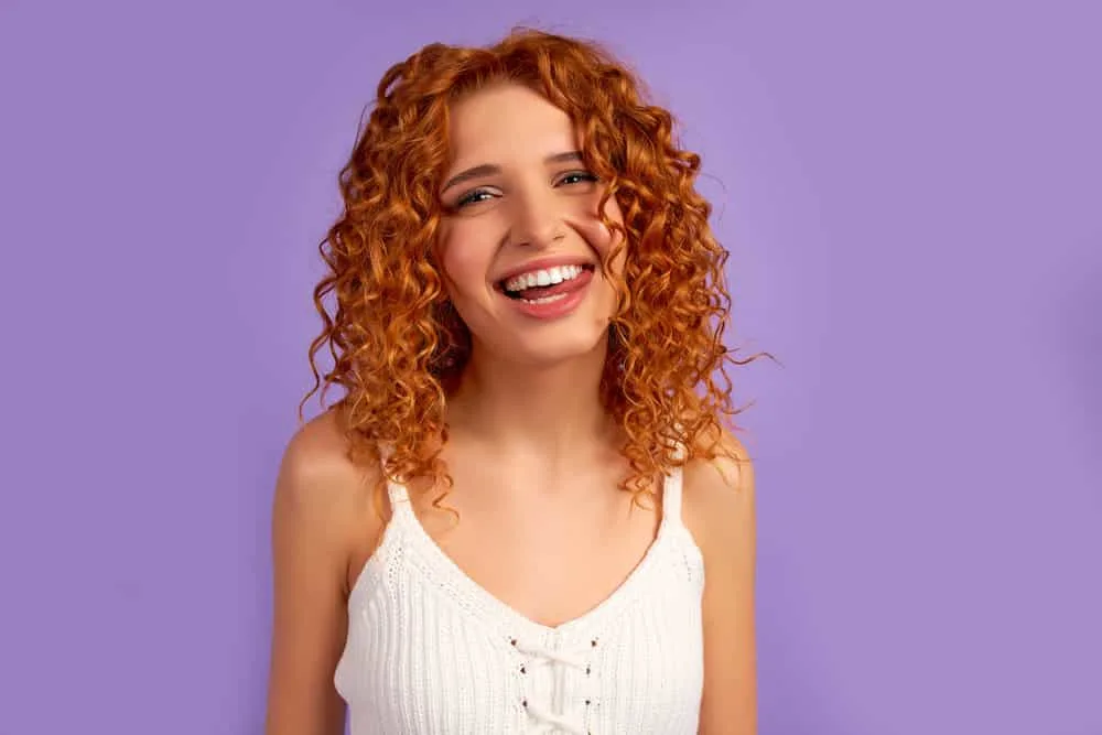 Can I Use Purple Shampoo on Orange Hair? Does It Work? 2 Red-haired girl with brassy hair headed to the hair salon to have it treated with blue shampoos by a hair professional.